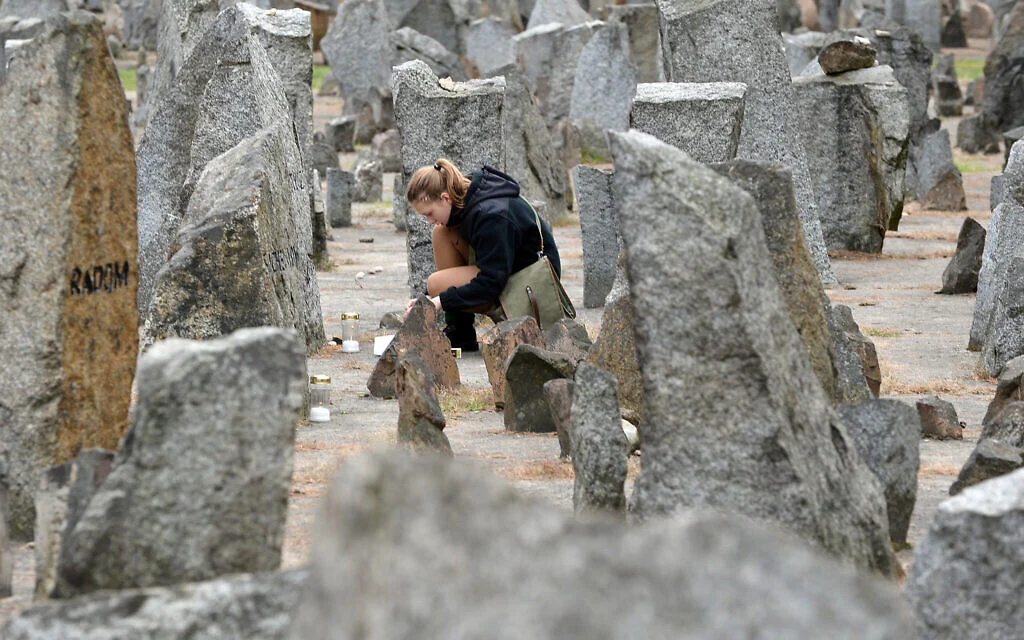 A Polish scout lights a candle in front of the monument of Treblinka